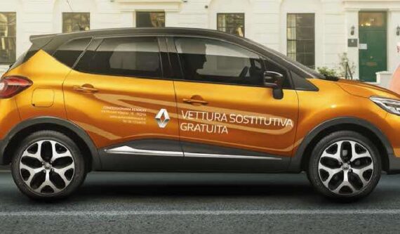auto renault di profilo su strada con marchio renault e scritta vettura sostitutiva gratuita sulla portiera del passeggero